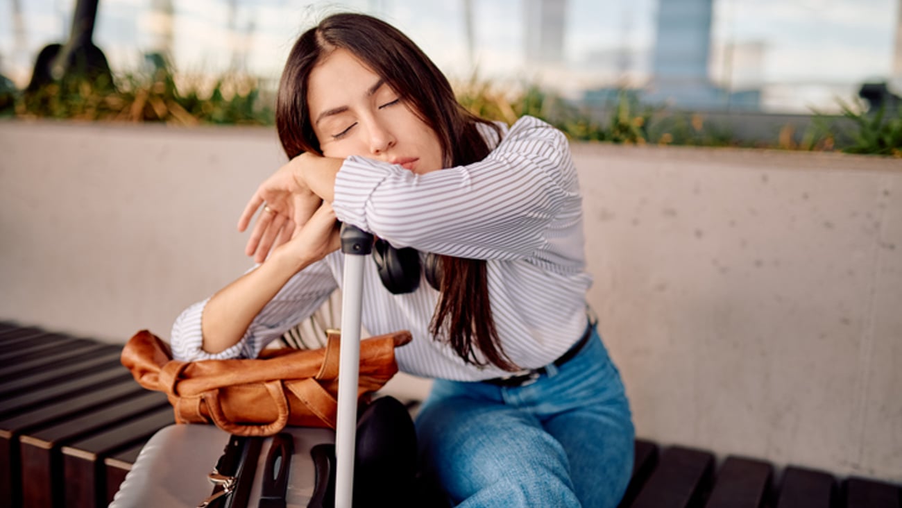 Une femme voyage avec sa valise et est fatiguée par le décalage horaire