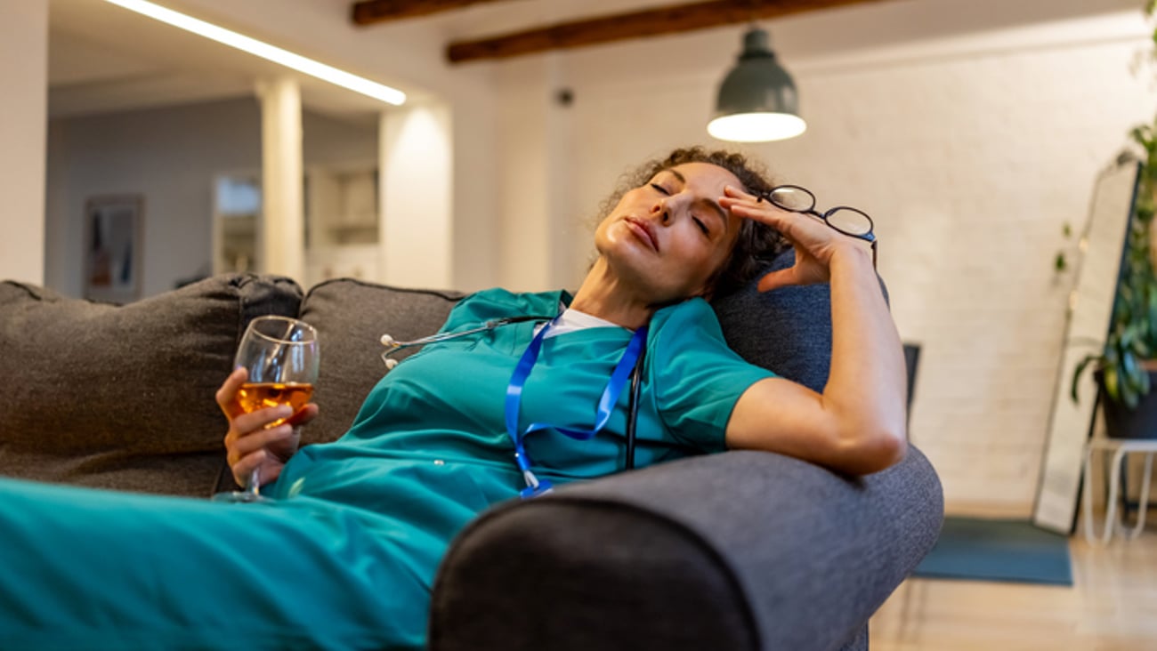 Une femme médecin fatiguée tient dans sa main un verre d'alcool