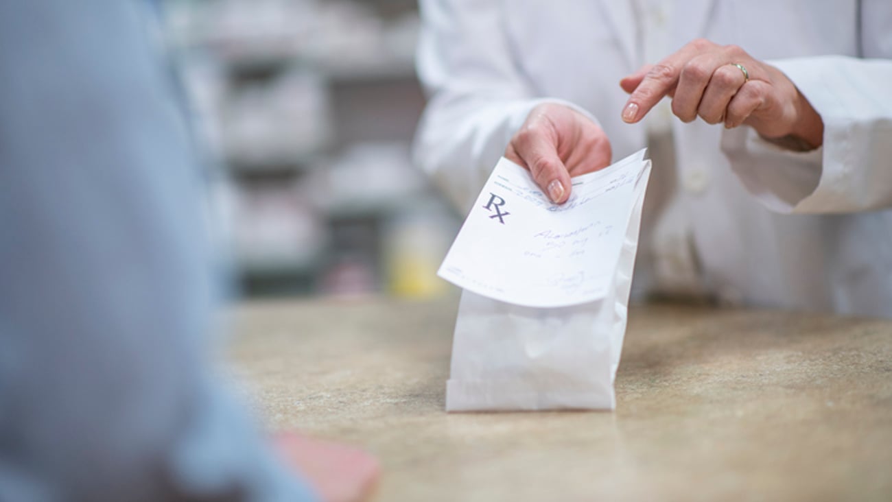 Une pharmacienne remet un sac de médicaments à son client