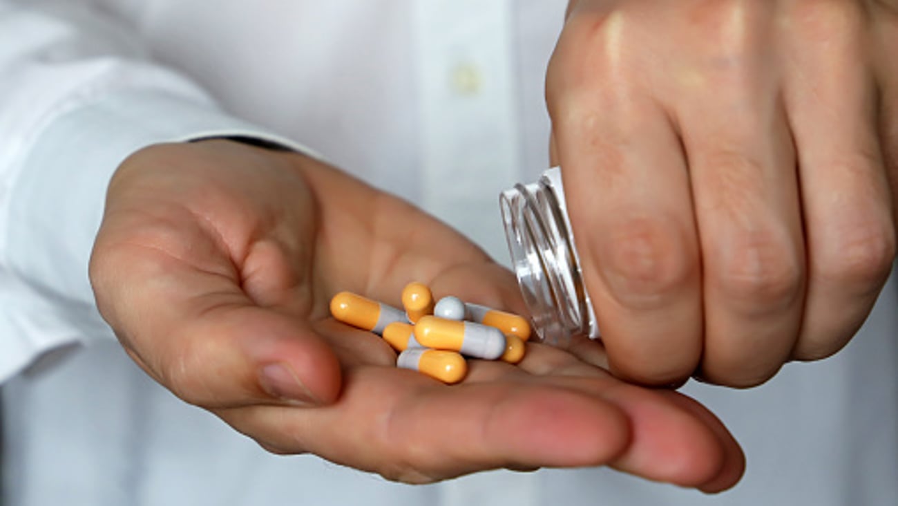 Les mains d'un médecin ou d'un pharmacien versant des capsules de médicaments