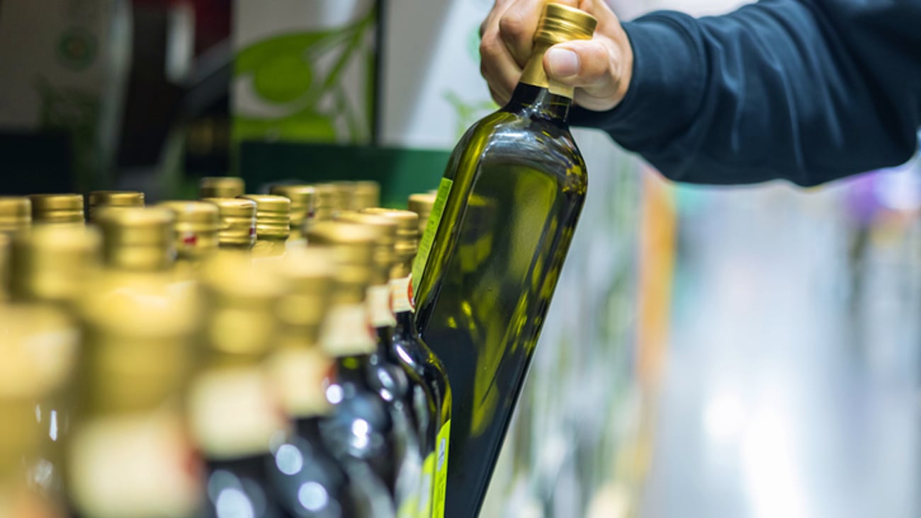 Un homme achète de l'huile d'olive à l'épicerie