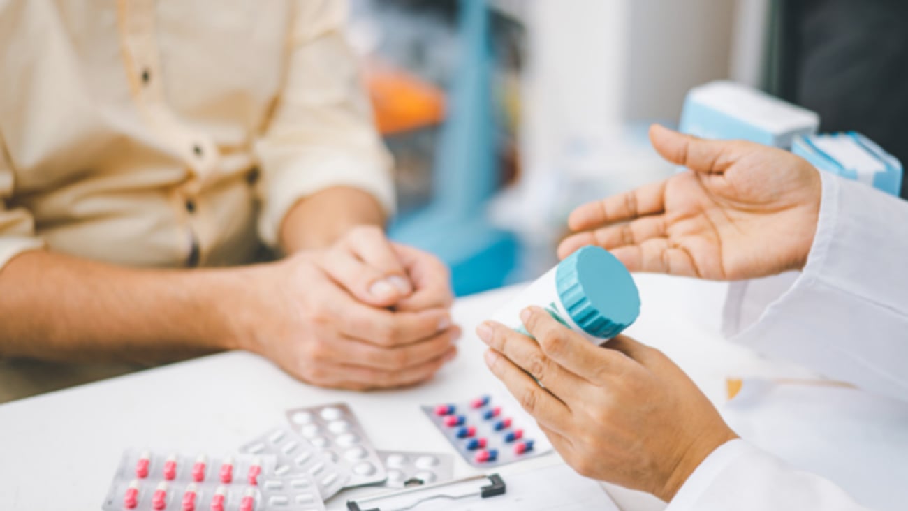 Un pharmacien donne des informations et des conseils à un client à propos de son traitement.