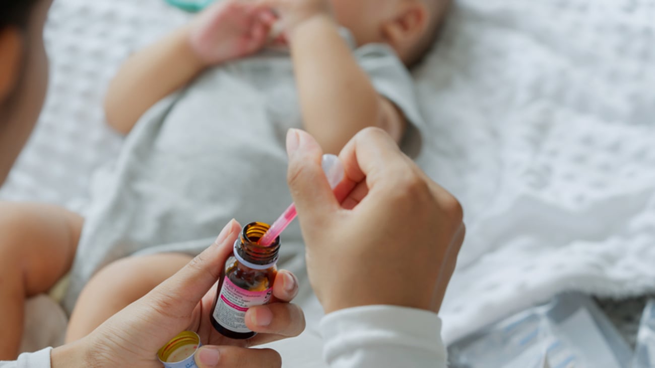 Une mère prépare une dose de médicament rose pour son nourrisson