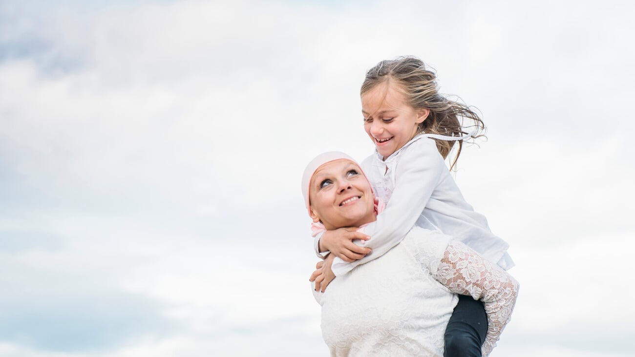 A woman with cancer is next to her daughter. A girl is hugging a woman happy; Shutterstock ID 1024149976