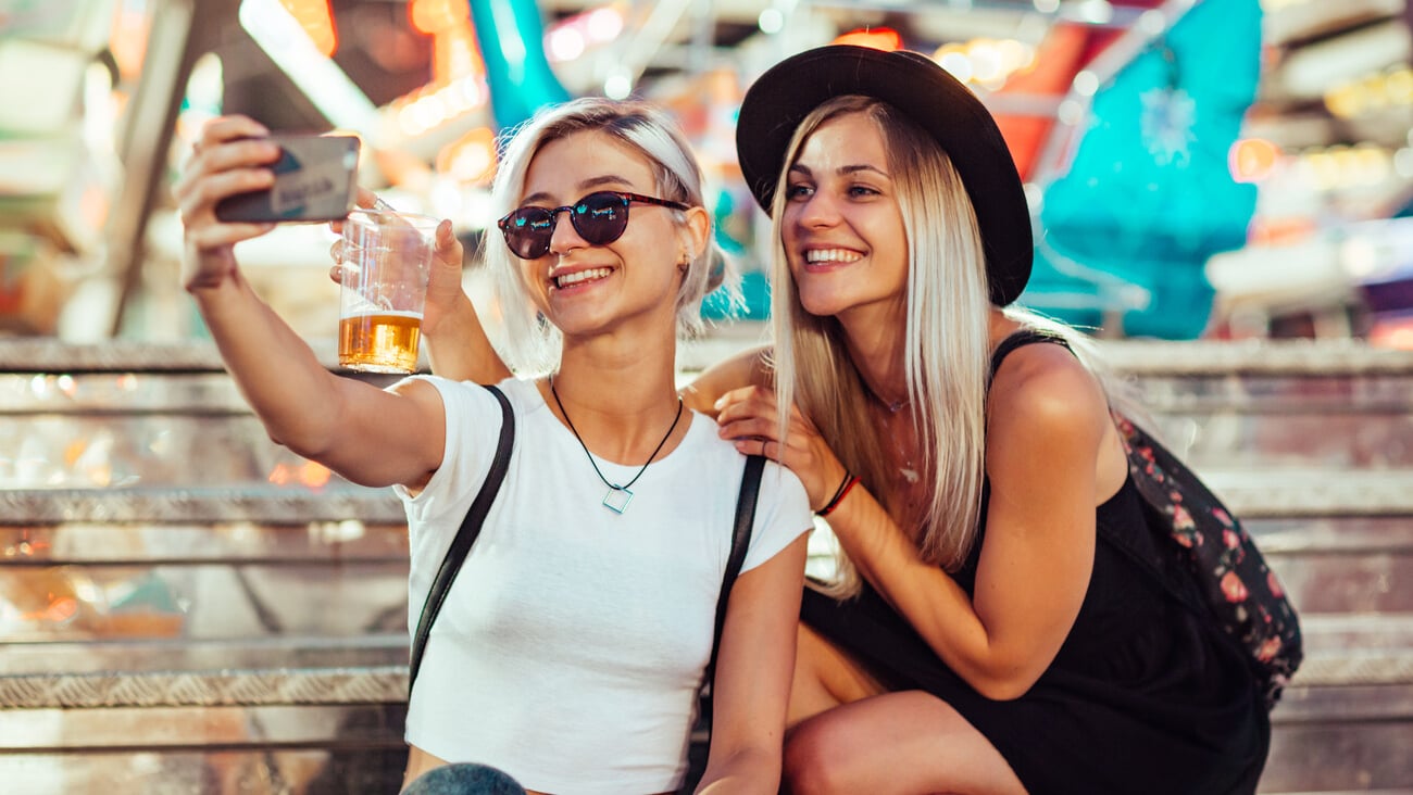 Happy female friends in amusement park taking selfie. Two young women enjoying night at amusement park.; Shutterstock ID 1198085971