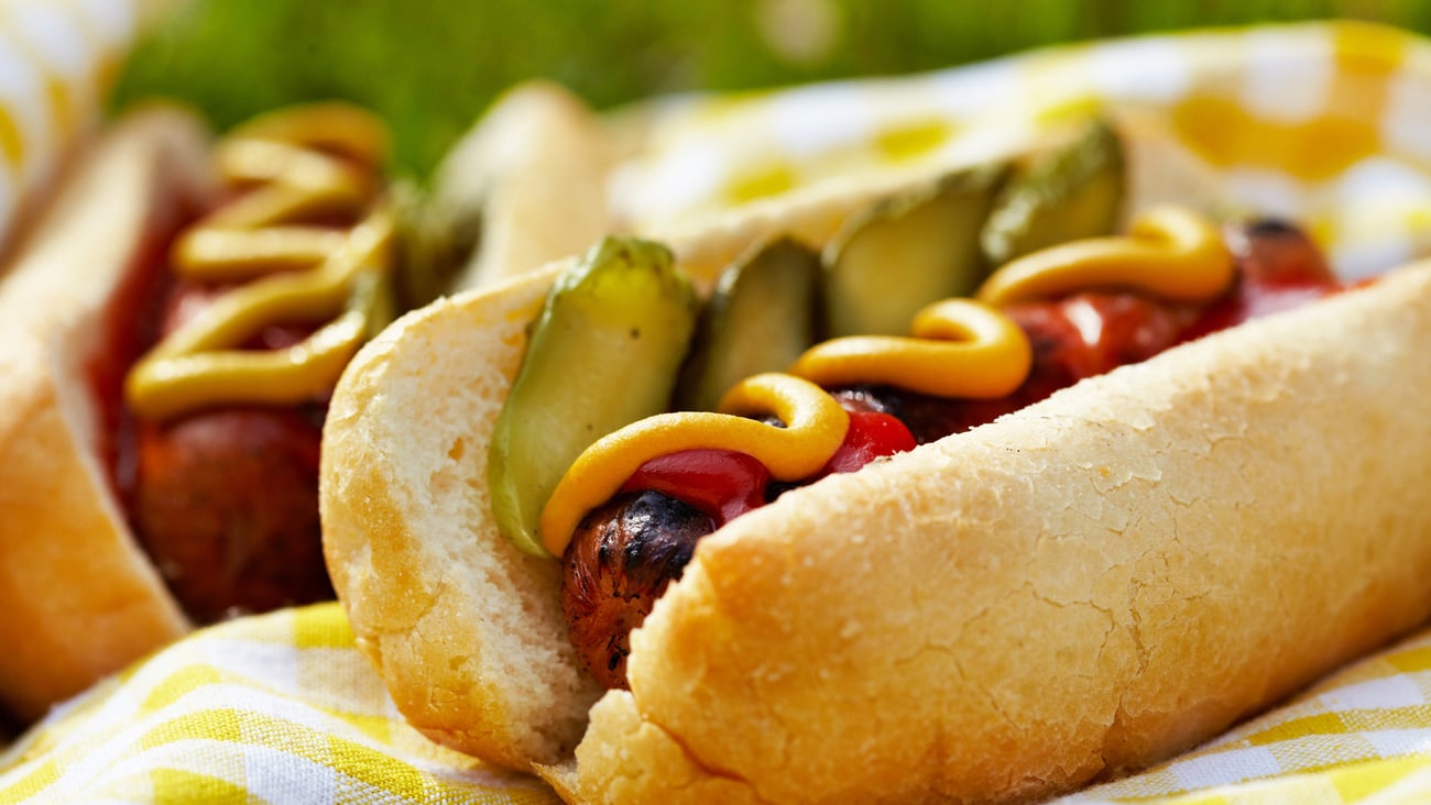 Grilled hot dogs with mustard, ketchup and relish on a picnic table; Shutterstock ID 139728997