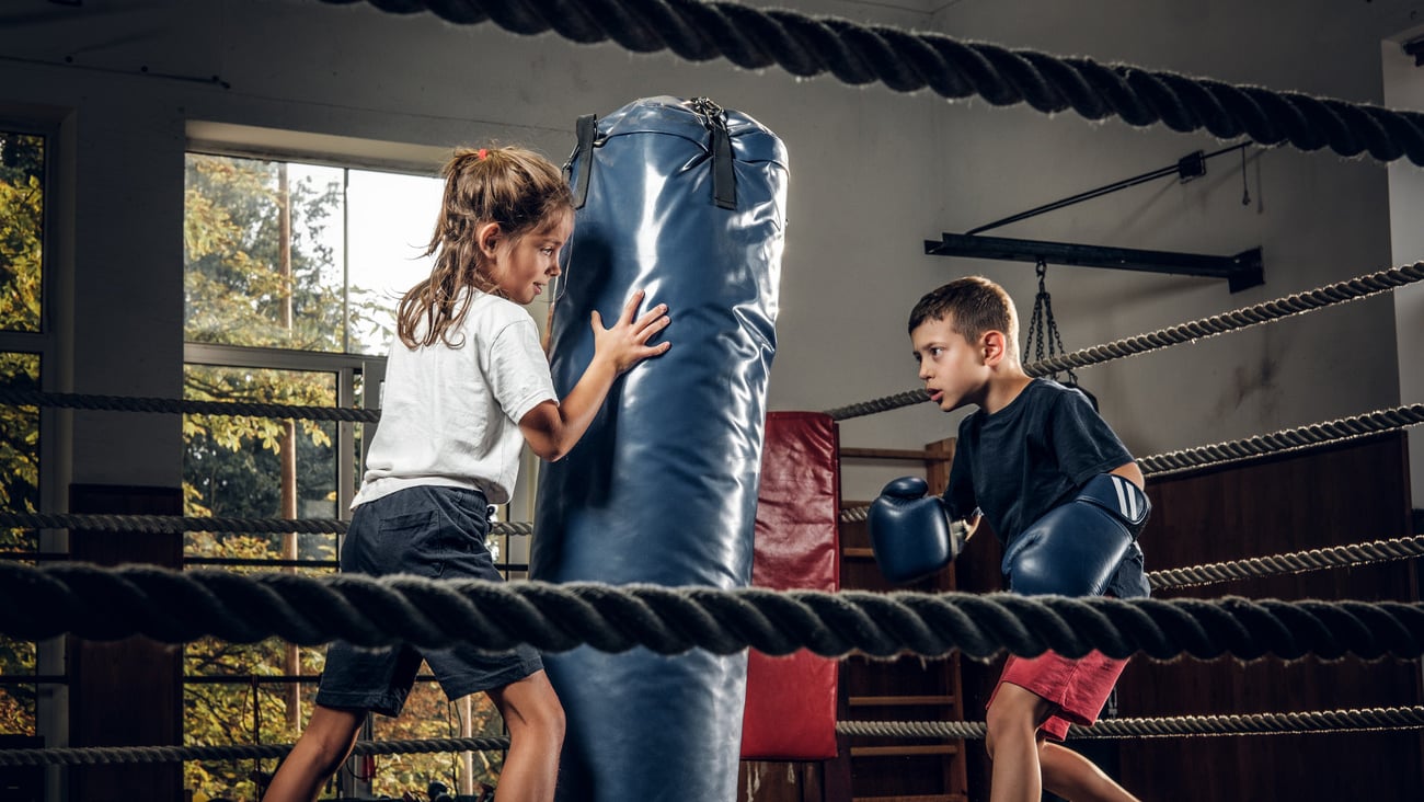 Dark photo shoot of kids training with big punching bag at boxing studio.; Shutterstock ID 1508087285