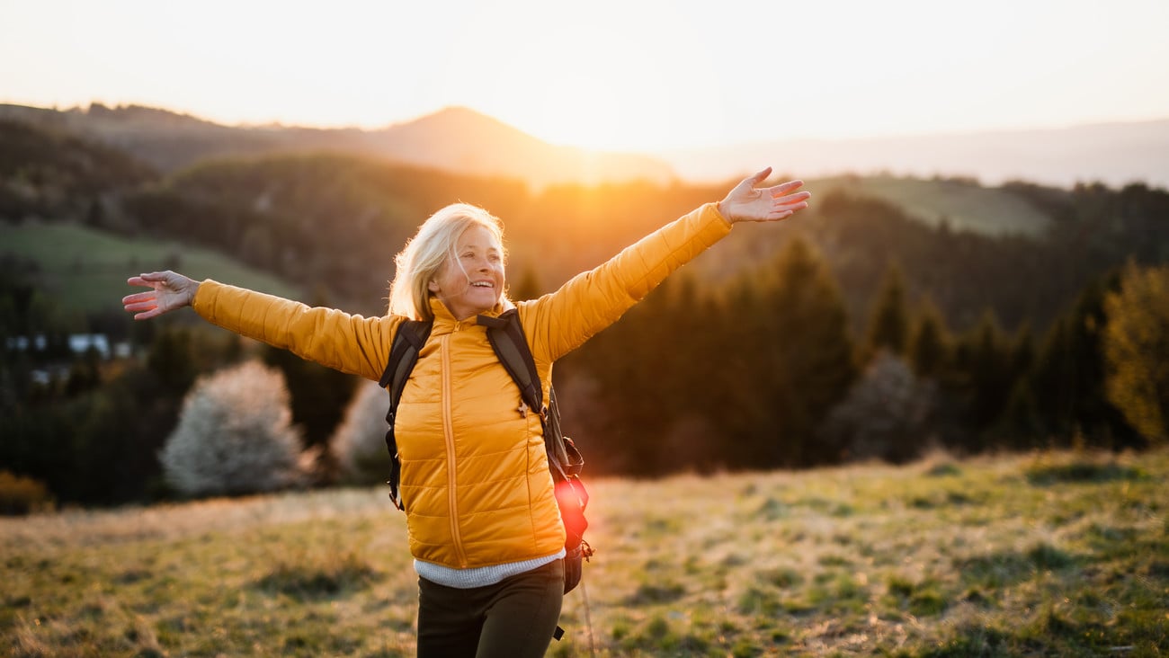 Front view of senior woman hiker standing outdoors in nature at sunset.; Shutterstock ID 1746068339