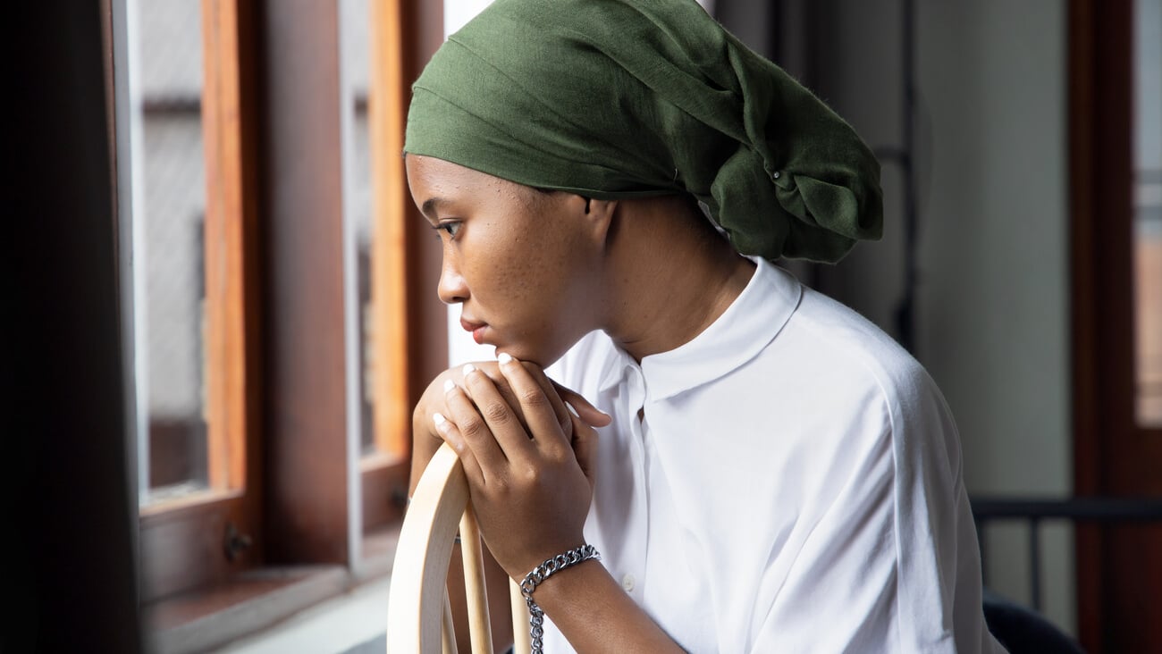 Portrait of sad African young woman cancer patient fighting with the sickness, wearing head scarf after suffering serious hair loss side effect due to chemotherapy, concept of cancer awareness; Shutterstock ID 1823686478