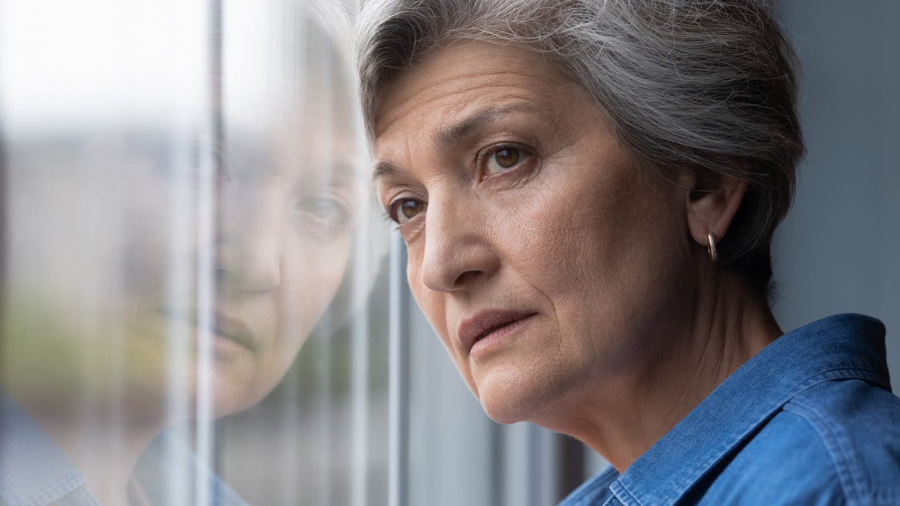 Close up head shot frustrated middle aged 60s woman standing near window, looking in distance, feeling depressed indoors. Unhappy mature senior lady suffering from personal problems or loneliness.; Shutterstock ID 1877565820
