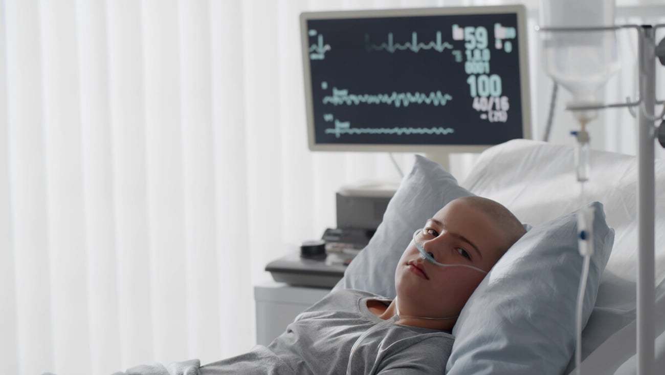 Teenage bald boy lying in hospital with oxygen tube. Side view of kid patient in oncology clinic resting in bed having chemotherapy treatment in ward; Shutterstock ID 1921349135