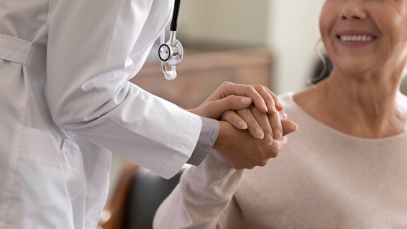Doctor giving hope. Close up shot of young female physician leaning forward to smiling elderly lady patient holding her hand in palms. Woman caretaker in white coat supporting encouraging old person; Shutterstock ID 1971115256