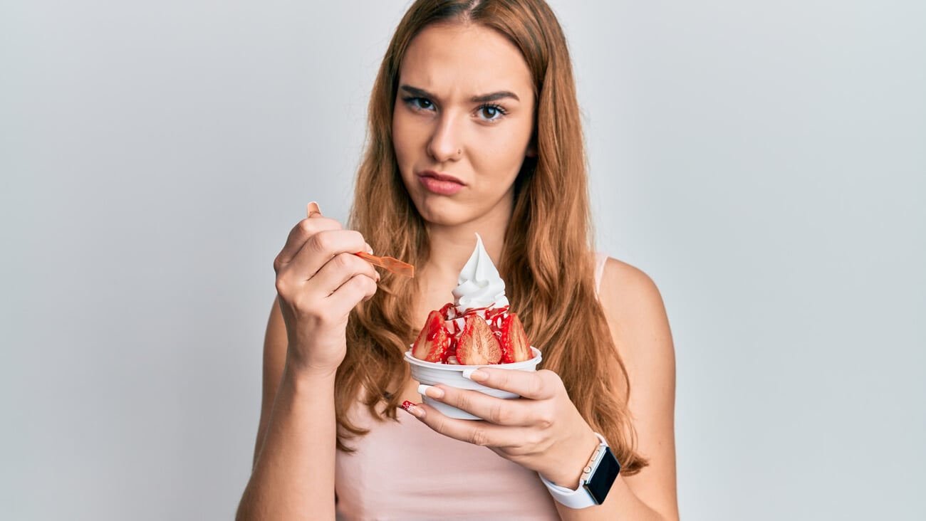 Young blonde woman eating strawberry ice cream skeptic and nervous, frowning upset because of problem. negative person. ; Shutterstock ID 2016656801
