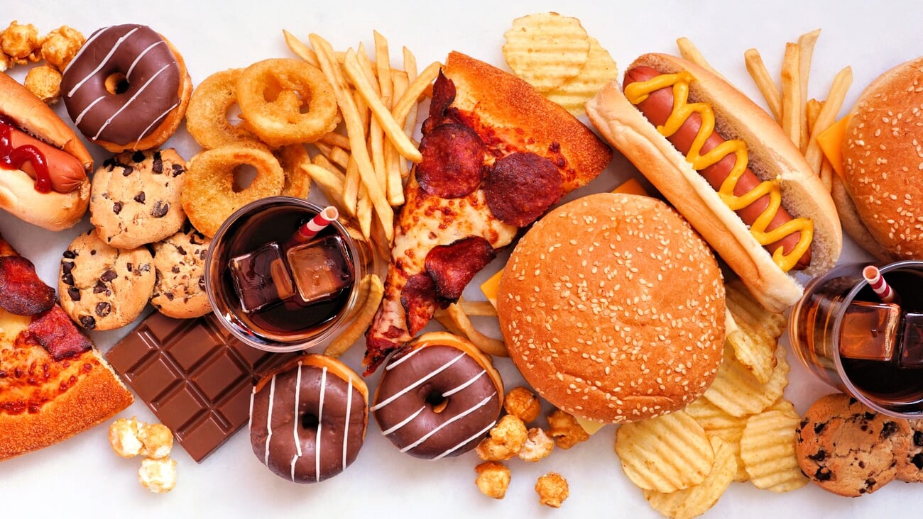 Junk food table scene scattered over a white marble background. Collection of take out and fast foods. Pizza, hamburgers, french fries, chips, hot dogs, sweets. Top view.; Shutterstock ID 2135456615