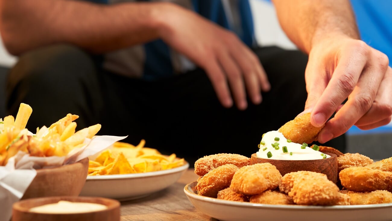 football fan eating snacks served on a wooden table; Shutterstock ID 2221002161