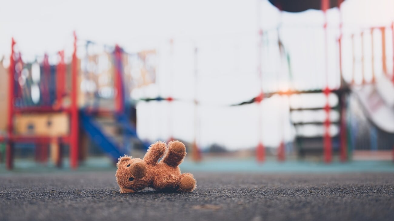 Lost teddy bear toy lying  on playground floor in gloomy day,Lonely and sad brown bear doll lied down alone in the park, Lost toy or Loneliness concept,International missing Children day; Shutterstock ID 2269475509