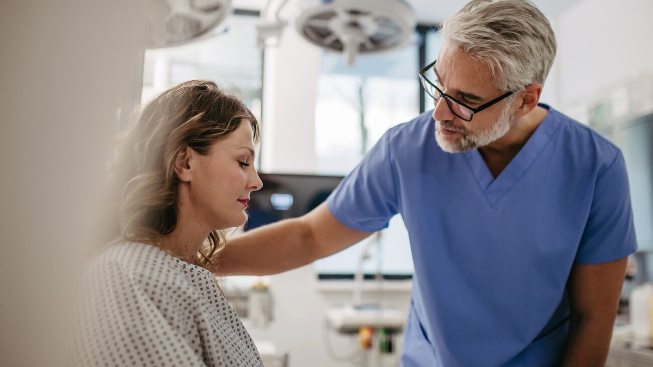 Supportive doctor soothing a worried patient, discussing test result in emergency room. Compassionate physician supporting stressed patient.; Shutterstock ID 2424433129