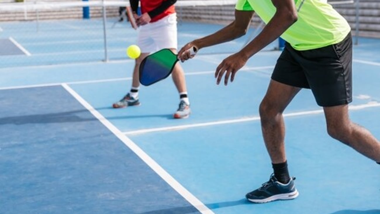 Close-up of a multiracial group of pickleball players focused on hitting the ball during a game on a blue outdoor court. Concept of focus and teamwork.; Shutterstock ID 2512690981