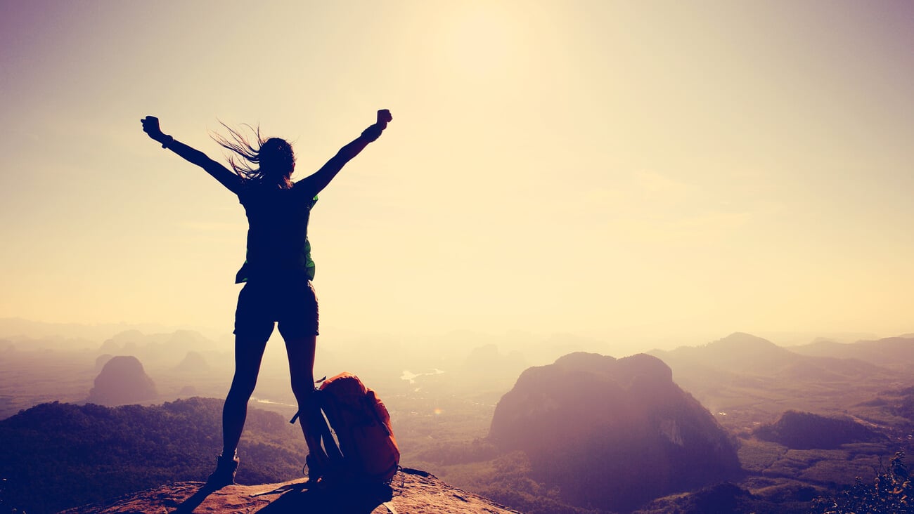 Silhouette of free cheering woman hiker open arms at mountain. top cliff edge; Shutterstock ID 396552382