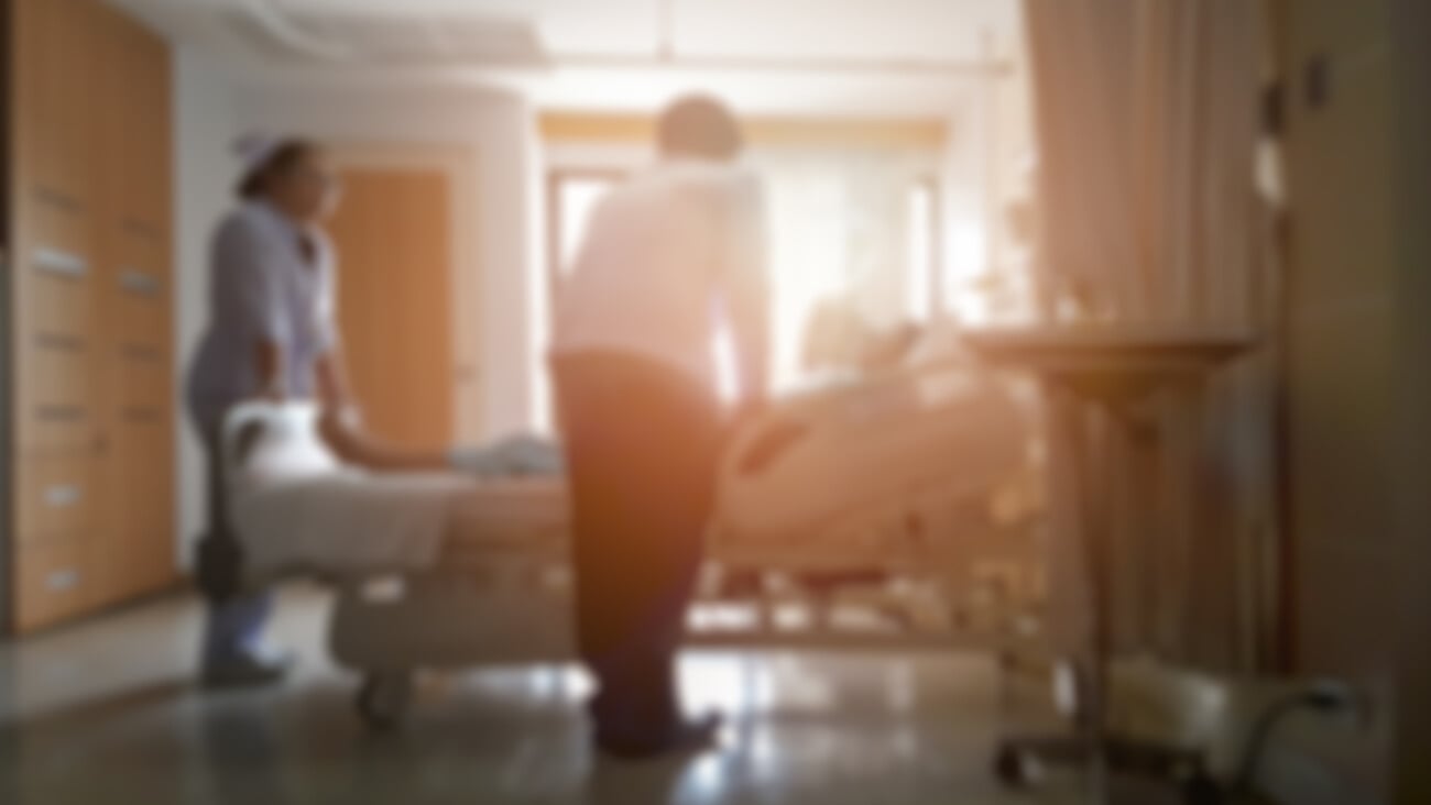 Doctor and nurse talking with patient lying in bed, Blurred hospital room image with sunset light effect between Doctor and Patient; Shutterstock ID 774940648