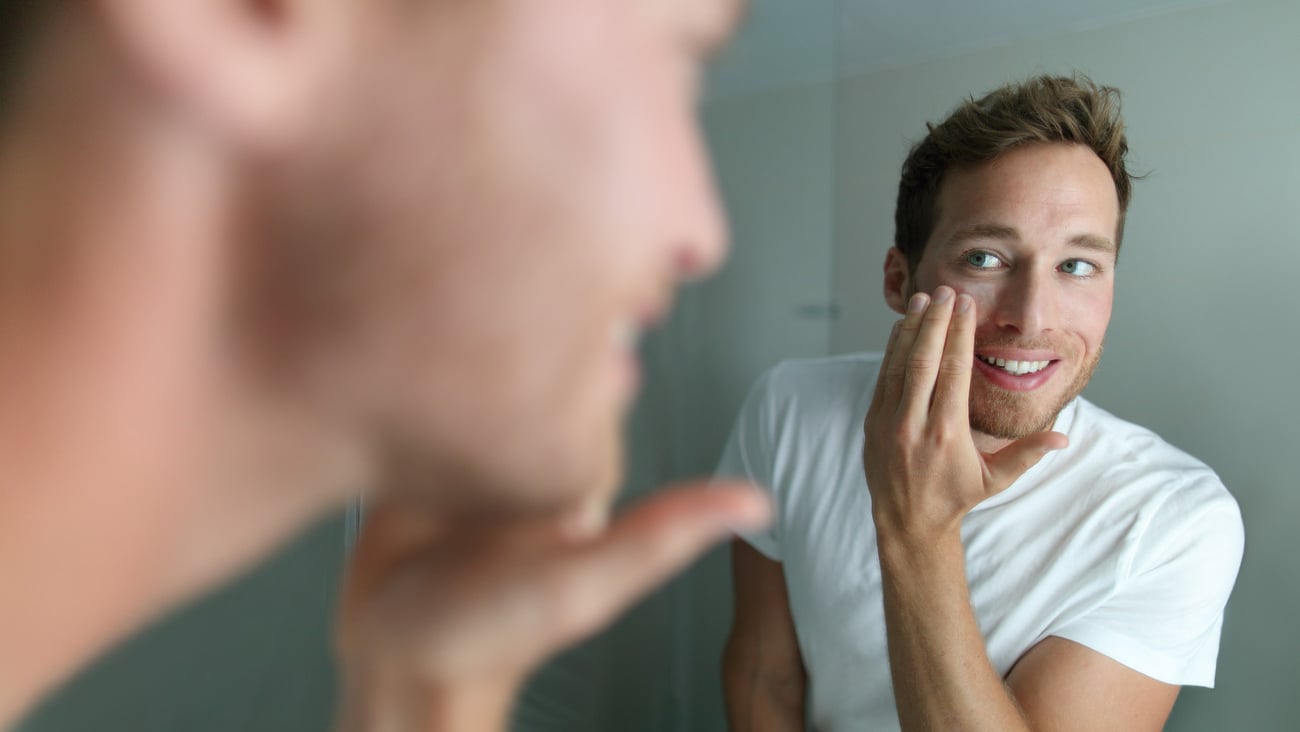 Face cream young man putting skincare beauty product on face hydrating skin. Male beauty facial treatment care at home lifestyle. Person applying moisturizer for dry skin during winter.; Shutterstock ID 790243321