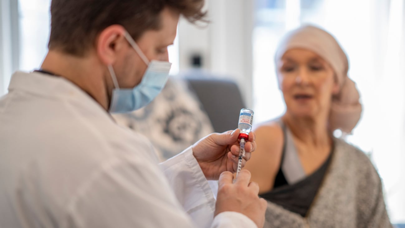 Une patiente atteinte d'un cancer se fait vacciner par un professionnel de la santé.