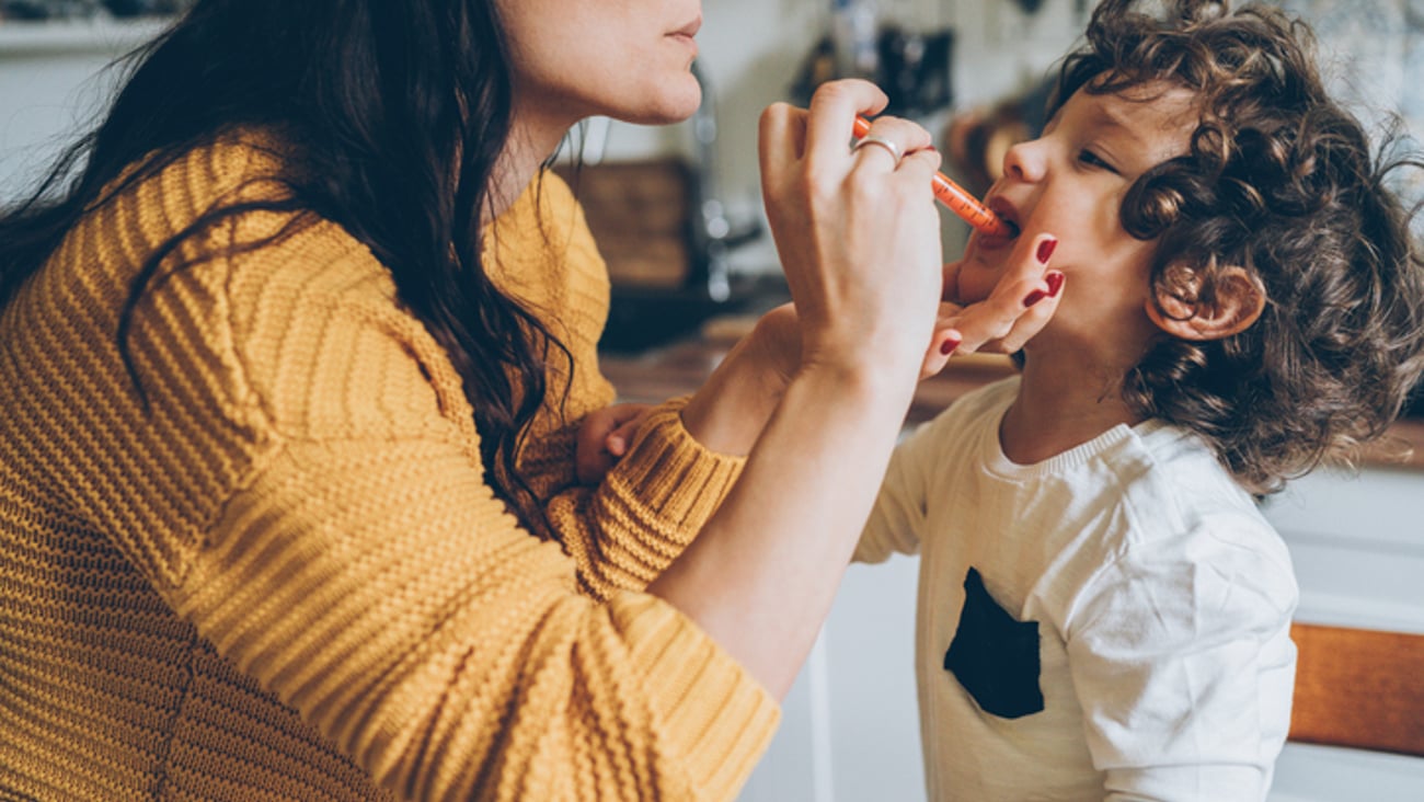 Une mère administre un médicament liquide à son enfant.