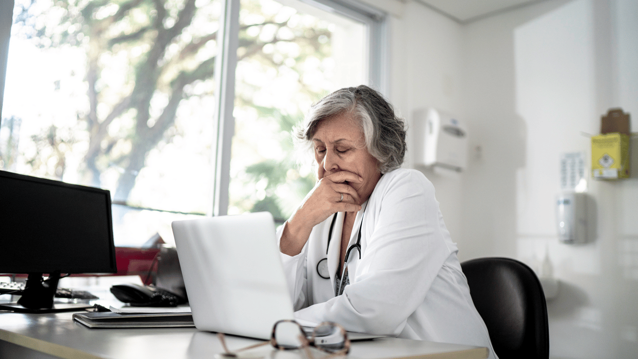 Entre réflexion et stupéfaction, une médecin est assise devant son ordinateur.