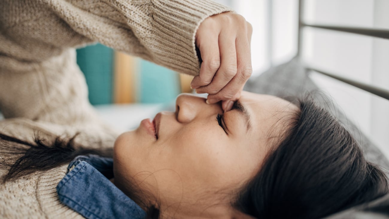 Une femme souffrant de migraine est couchée sur un divan.