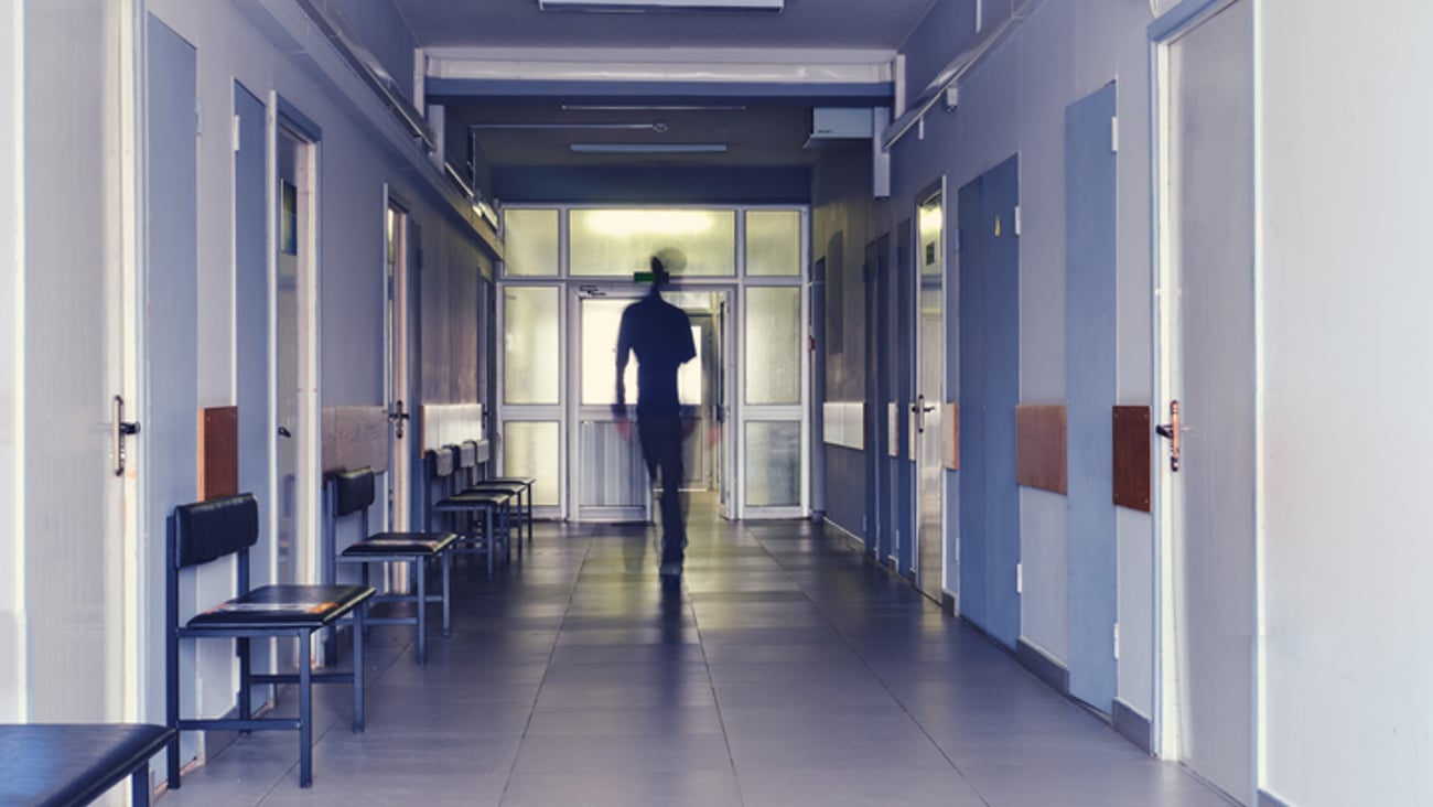 La silhouette floue d’un homme quittant un hôpital.