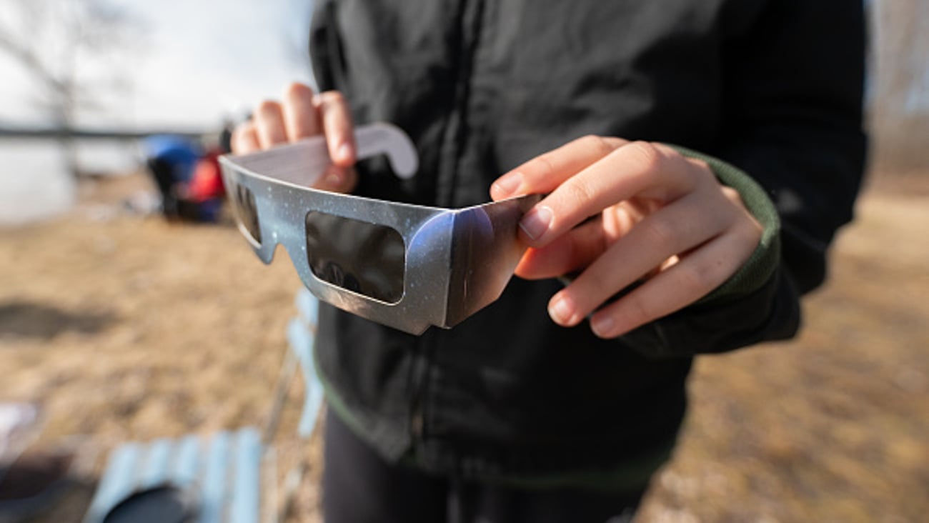 Une personne tient les lunettes spécifiquement conçues pour protéger les yeux pendant l'éclipse solaire nord-américaine du 8 avril 2024.