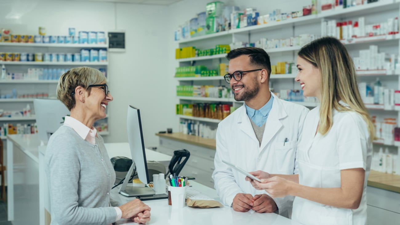 Deux pharmaciens discutent avec une patiente au comptoir