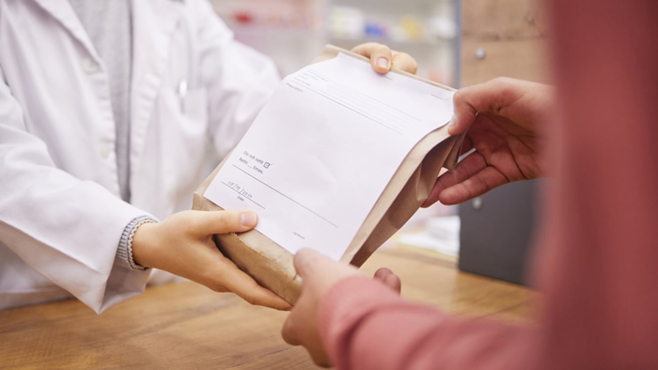 une pharmacienne remet un paquet de médicaments à un client