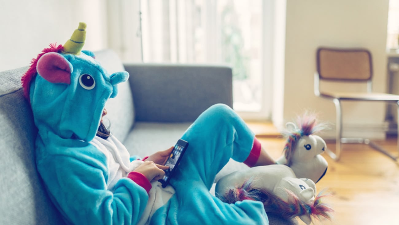 Un enfant joue sur un téléphone, assit sur un divan.