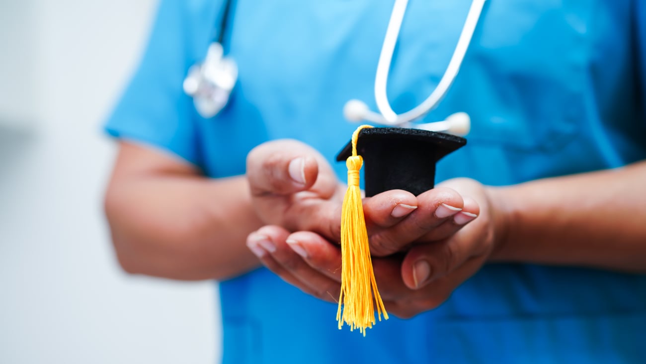 Une étudiante tient un chapeau de graduation.