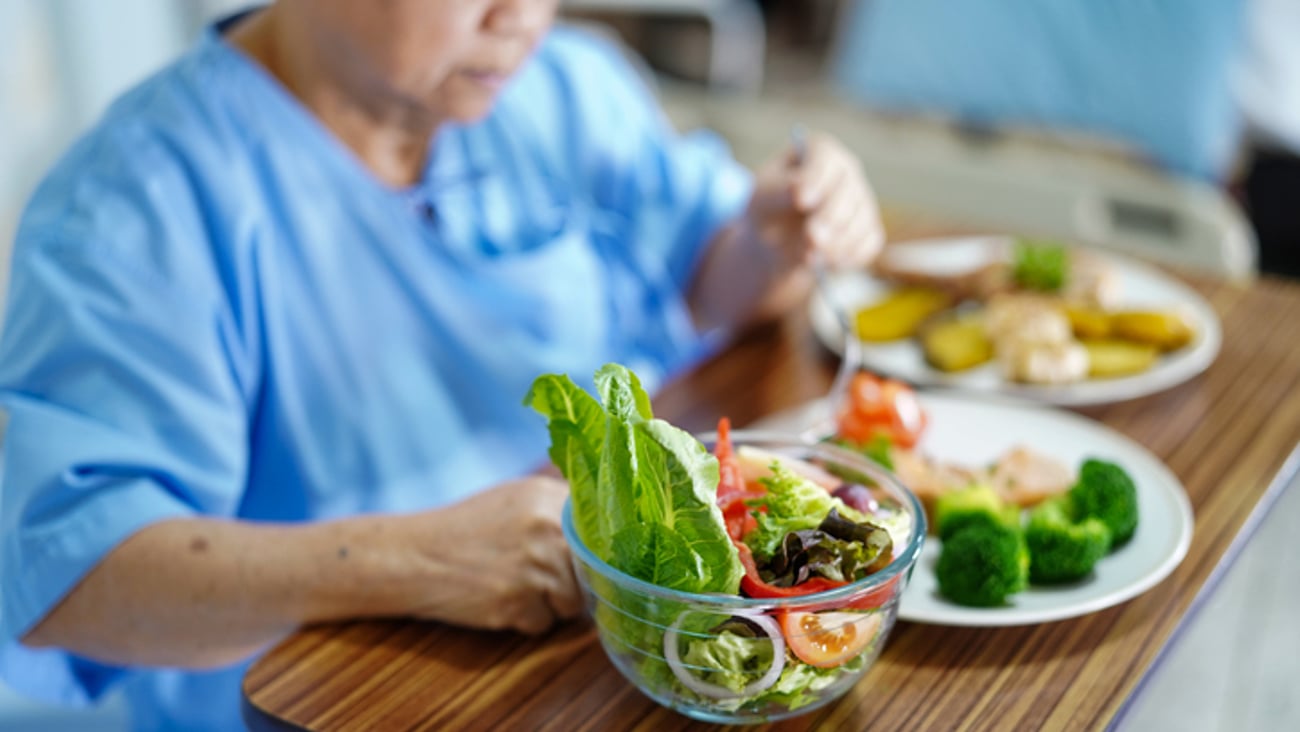 Une patiente mange un repas dans son lit à l'hôpital.