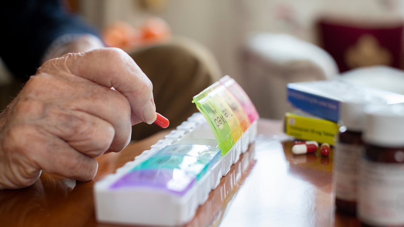 Un aîné organise ses médicaments dans son pilulier.