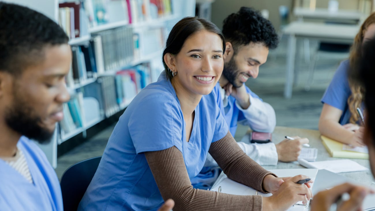 Des étudiants en médecine discutent dans une bibliothèque.