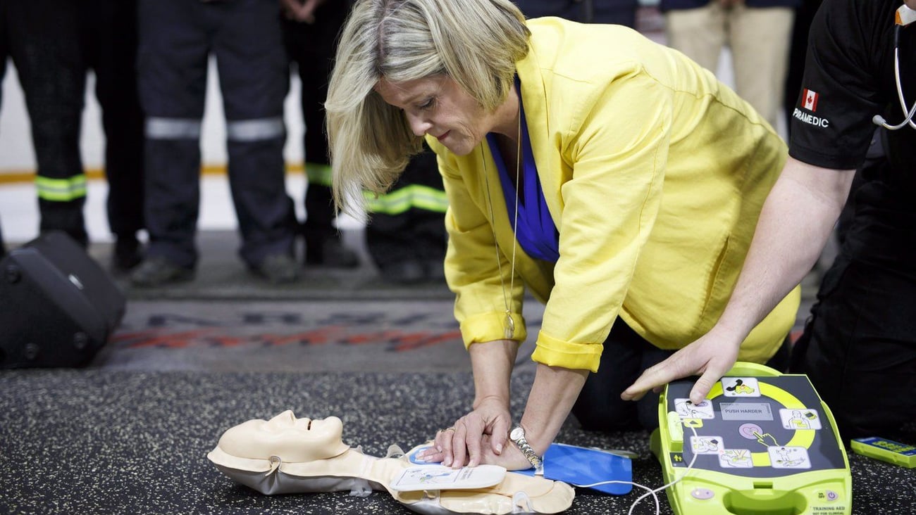 La cheffe du NPD de l'Ontario, Andrea Horwath, fait la démonstration d'un défibrillateur externe automatique sur un mannequin, aux côtés du président du syndicat des paramédics de Peel, Dave Wakely, à Brampton, en Ontario. PC/Cole Burston