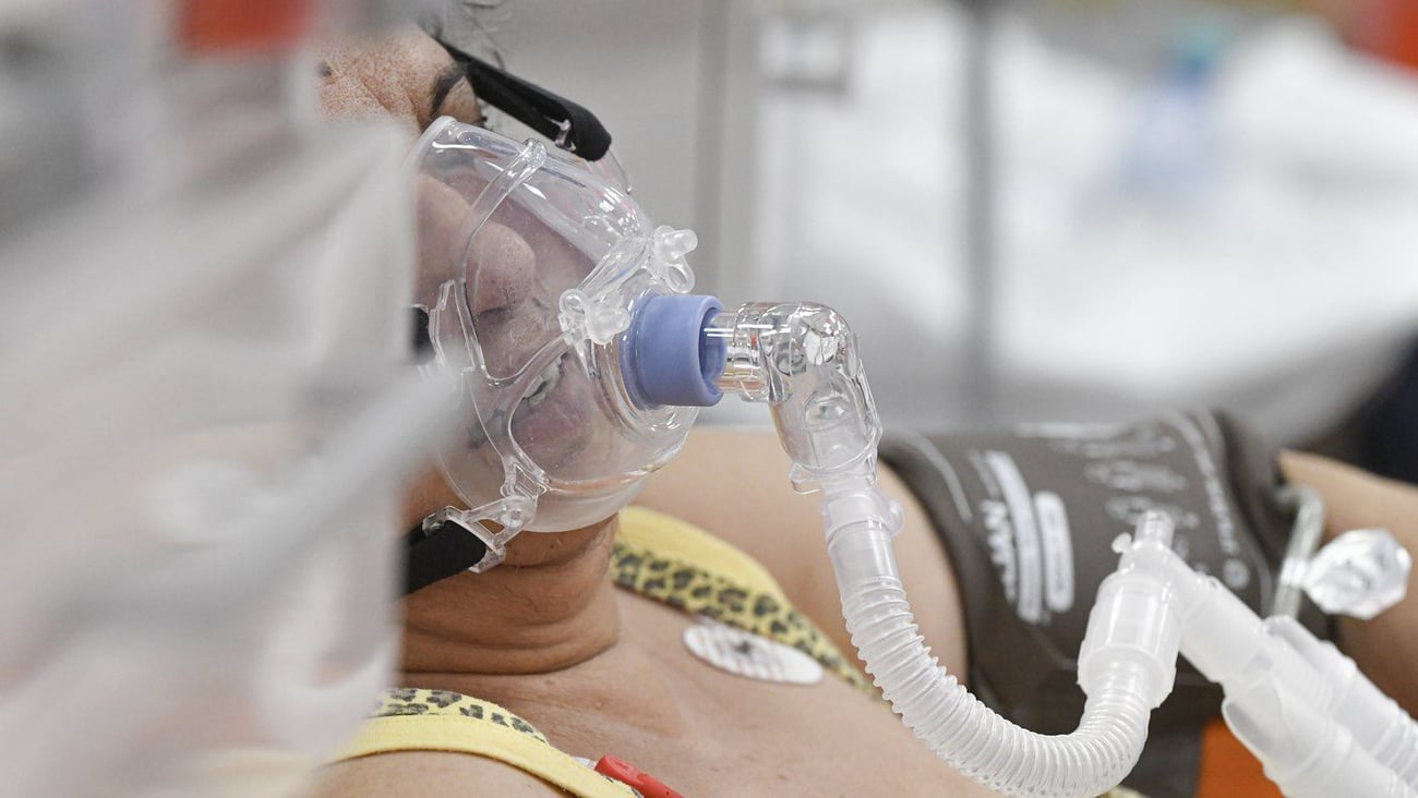 Une femme respire à travers un masque à oxygène. (AP Photo/Andreea Alexandru). 