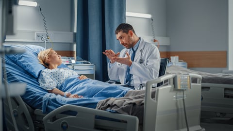 Un médecin spécialiste donne des explications à sa patiente, dans son lit d'hôpital.