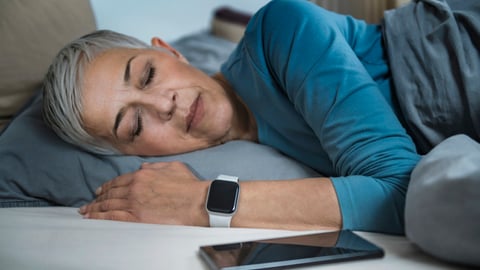 Une femme porte une montre dotée d'une application de suivi du sommeil.