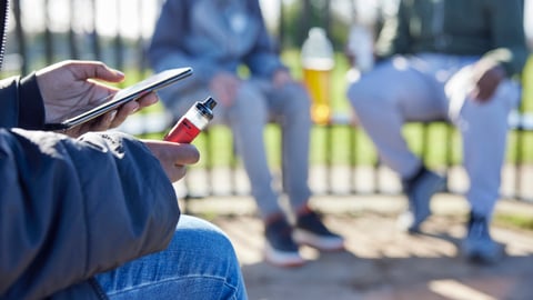 Adolescents en train de vapoter dans un parc.