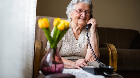 Une aînée parle au téléphone assise.