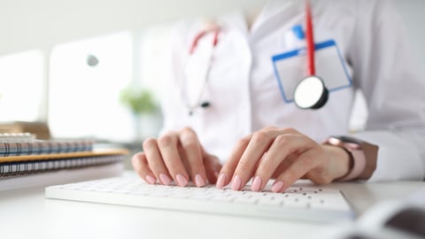Mains d'une médecin sur un clavier d'ordinateur