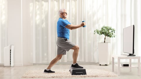 Un homme fait de l'exercice avec un step devant la télévision.