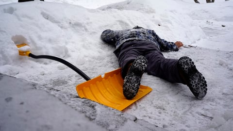 Un homme est étendu sur le sol à côté d'une pelle à neige