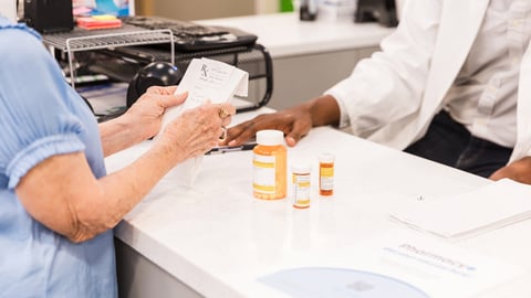 Une patiente âgée vient récupérer ses médicaments en pharmacie