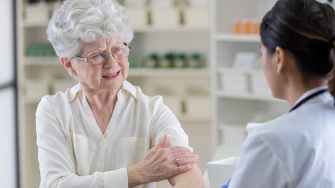 Une personne âgée souffre d'une douleur au bras, à la pharmacie.