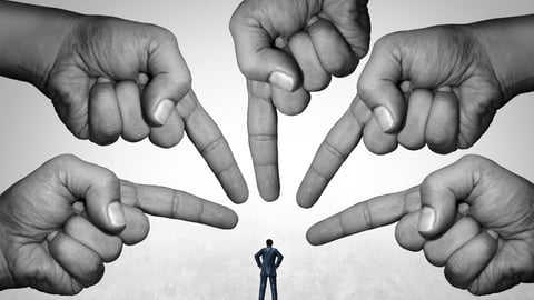 Plusieurs mains pointent une personne en la tenant pour responsable